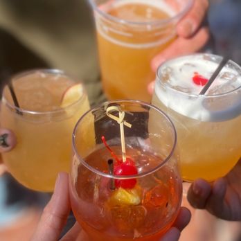 Apple Dave's Distillery - a close up of a hand holding three glasses of cocktails - Distilleries Near Me - Warwick, New York Apple Dave's Distillery - a close up of a hand holding three glasses of cocktails - Distilleries Near Me - Warwick, New York