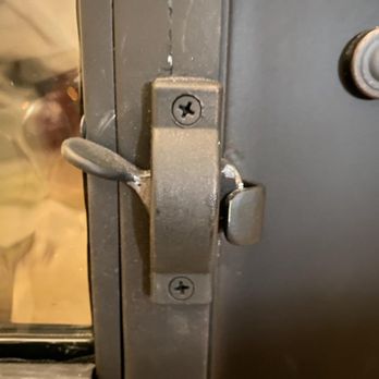 Durango Doors - A detailed view of a metal latch and lock mechanism attached to a door or window frame, with visible screws and hardware. - Door Sales/Installation Near Me - Austin, Texas