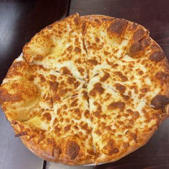 Georgian Chef - cheese bread - A cheese bread with a melted, golden-brown cheese topping is shown on a dark wooden table, with a small portion of a white plate visible at the top. - Georgian Near Me - Howell, New Jersey