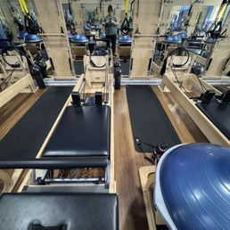 View of a reformer bed plus some other equipment such as a mat, TRX straps, balance ball, etc.