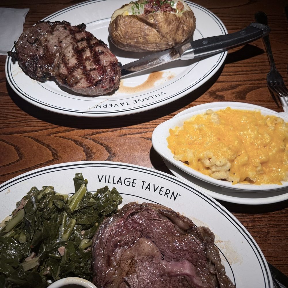 Village Tavern - Delmonico Rib Eye (14oz) with loaded baked potato and sautéed spinach. Prime rib with macaroni and cheese and sautéed collards. - New American Near Me - Winston-Salem, North Carolina