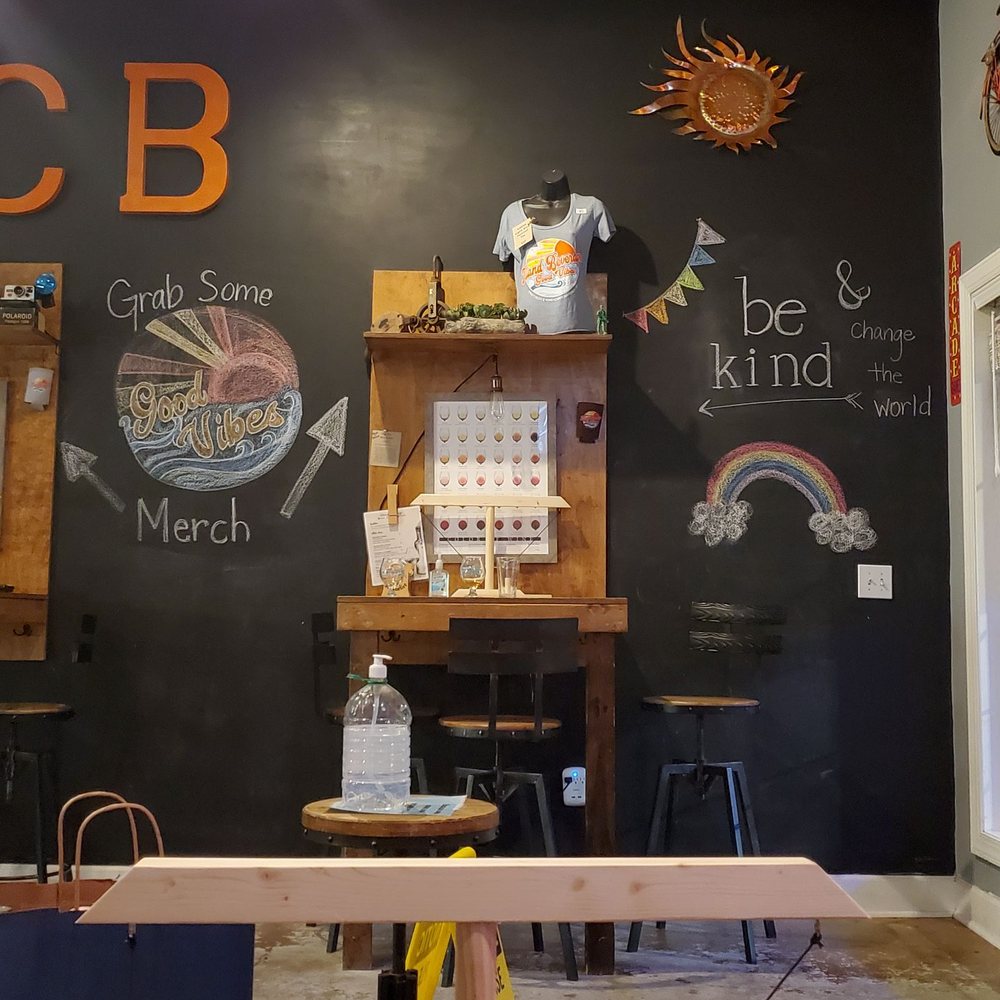 Island Beverage - a chalkboard wall with a chalkboard sign and a table with stools in front of it - Beer, Wine & Spirits Near Me - Carolina Beach, North Carolina