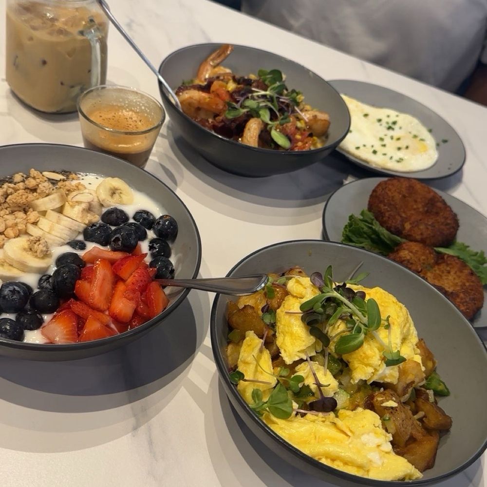 Early Bird Cafe - Shrimp and grits, side of eggs, yogurt parfait, garden harvest bowl and crab cakes. Drinks are a cortado and iced latte. - Breakfast & Brunch Near Me - Richmond, Texas