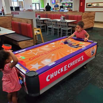 Chuck E. Cheese - two children playing a game of air hockey - Pizza Near Me - Oklahoma City, Oklahoma Chuck E. Cheese - two children playing a game of air hockey - Pizza Near Me - Oklahoma City, Oklahoma