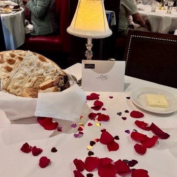 The Capital Grille - Rose petals on the table for our anniversary (plus bread basket) - Steakhouses Near Me - Livonia, Michigan