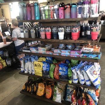 HTeaO - Snacks and Yeti merchandise - Shelves stocked with YETI tumblers, snack bags, and other merchandise at a retail store, with two children at the counter. - Coffee & Tea Near Me - Georgetown, Texas