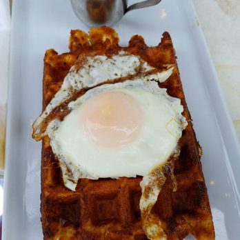 Leonidas Chocolate Cafe - Belgian Waffle topped with an egg, and served with syrup on the side. - Chocolatiers & Shops Near Me - Northbrook, Illinois Leonidas Chocolate Cafe - Belgian Waffle topped with an egg, and served with syrup on the side. - Chocolatiers & Shops Near Me - Northbrook, Illinois