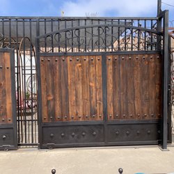 Los Gatos Fencing and Deck - Custom wrought iron gates with tong and groove red wood vertical boards in the center.