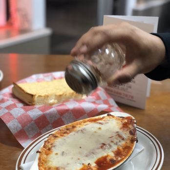 Jim's Pizza - a person sprinkling cheese on a dish - Pizza Near Me - Durand, Michigan Jim's Pizza - a person sprinkling cheese on a dish - Pizza Near Me - Durand, Michigan