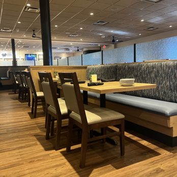 Bonefish Grill - Newly designed Bonefish Grill - A restaurant interior featuring wooden tables and chairs, with a booth along the wall, and a wood-look floor. - Seafood Near Me - Independence, Ohio
