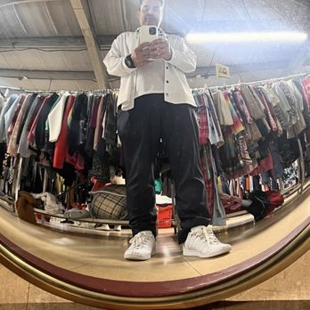 2nd Ave Thrift Superstore - Merch - A person is taking a mirror selfie in a thrift store, with clothing racks filled with various garments in the background. - Thrift Stores Near Me - Union, New Jersey