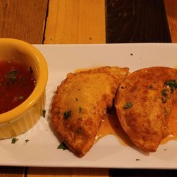 a white plate with two pieces of bread and a small bowl of sauce a white plate with two pieces of bread and a small bowl of sauce