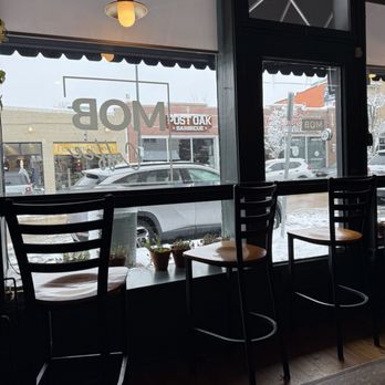 MOB Coffee - Inside a coffee shop, three chairs are positioned along a window overlooking a snowy street with parked cars and storefronts. - Coffee & Tea Near Me - Denver, Colorado