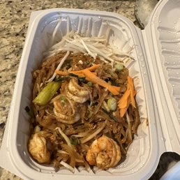 Pad Thai - A takeout container filled with shrimp pad Thai, including shrimp, bean sprouts, carrots, and green onions, placed on a granite countertop.