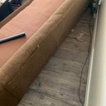 Joe Rushing - A brown upholstered bench is positioned along a wall in a room, with a wooden floor and some objects nearby. - Plumbing Near Me - Lubbock, Texas