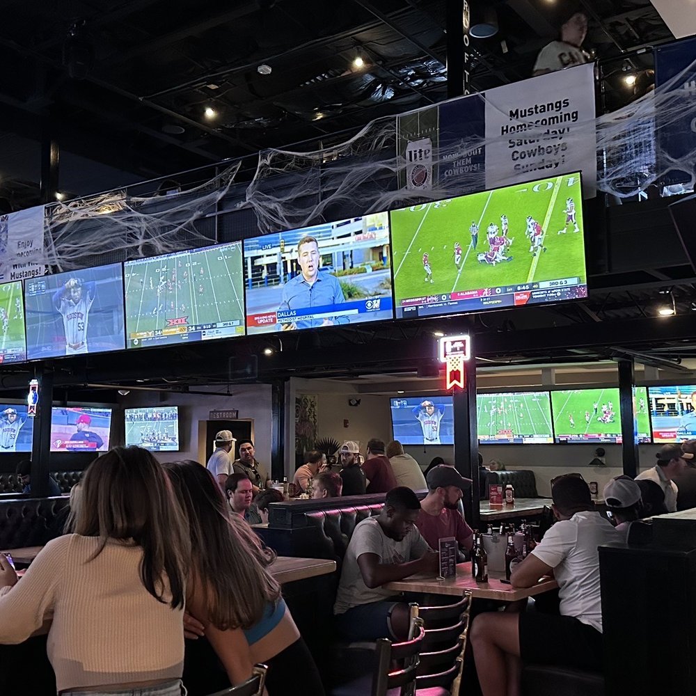 Christies - a group of people sitting at a bar watching televisions - Sports Bars Near Me - Dallas, Texas Christies - a group of people sitting at a bar watching televisions - Sports Bars Near Me - Dallas, Texas