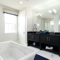 AMC Kitchen & Bath - This sophisticated bathroom features a black double vanity with silver hardware and integrated shelving...