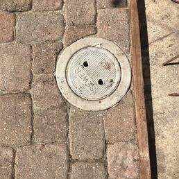 a manhole on a brick sidewalk