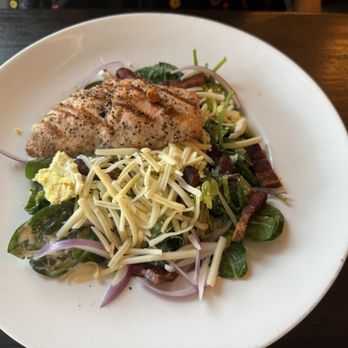River & Post - Salmon salad - A salmon salad featuring a grilled salmon fillet, shredded cheese, bacon bits, and mixed greens on a white plate. - Lounges Near Me - Jacksonville, Florida