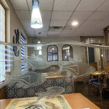 Mariscos Altamar - A glass fish-shaped partition divides tables inside a restaurant, with wooden tables and chairs visible in the background. - Mexican Near Me - Albuquerque, New Mexico