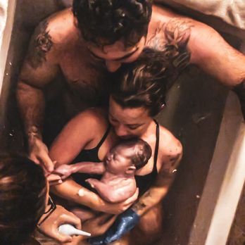 Moonchild Birth Services - First-time mom & dad with baby boy in birthing tub. Water birth at birth center - Doulas Near Me