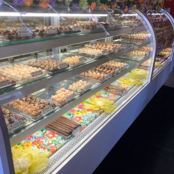 it! Candy - A glass display case showcases a variety of chocolates and candies, decorated with colorful floral paper and large artificial flowers. - Candy Stores Near Me - Bristol, Connecticut