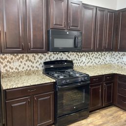 a kitchen with dark wood cabinets and a black stove a kitchen with dark wood cabinets and a black stove
