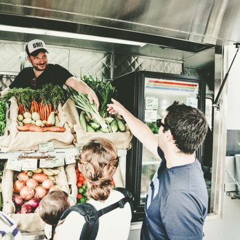 Grit Grocery - a man handing a bag of vegetables to a customer - Grocery Near Me Grit Grocery - a man handing a bag of vegetables to a customer - Grocery Near Me