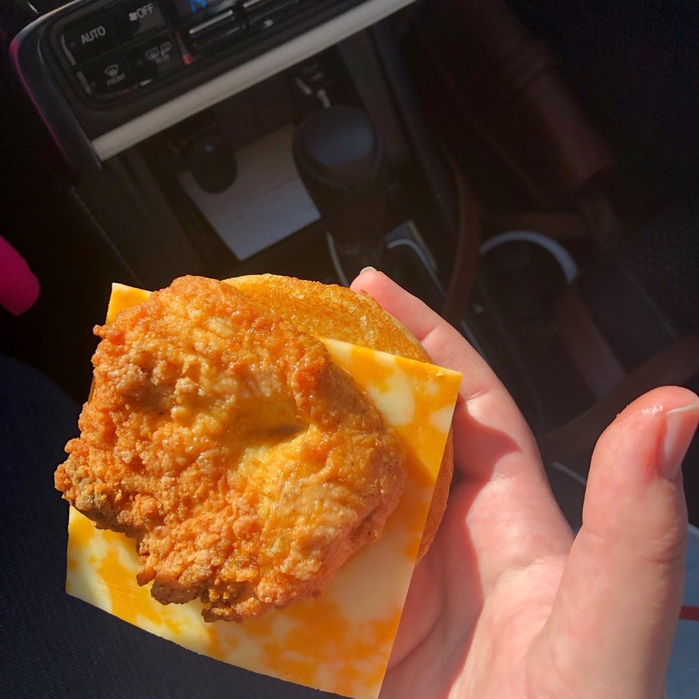 ows a hand holding a fried chicken sandwich ows a hand holding a fried chicken sandwich