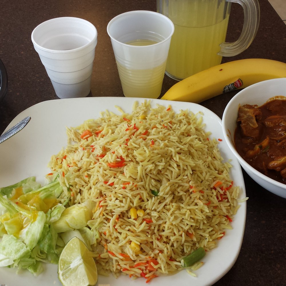 Darbo’s - Cup of free soup to the left, complimentary tea, pineapple juice,  banana, salad, curry rice, and curry goat.   All for $11. - African Near Me - Columbus, Ohio