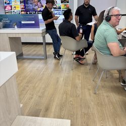 Xfinity Store by Comcast - Employee leisurely sitting back scrolling phone while colleague helpijg a customer. This is not a sign of respect.