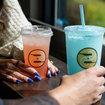 Ziggi's Coffee - Pink and blue iced dirty sodas in clear Ziggi's cups on a café table. - Coffee & Tea Near Me - Bentonville, Arkansas
