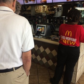 McDonald's - a man and a woman standing in front of a counter - Burgers Near Me - Concord, North Carolina