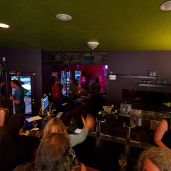 Volcanic Bottle Shoppe - a group of people standing around a bar - Bars Near Me - Hood River, Oregon