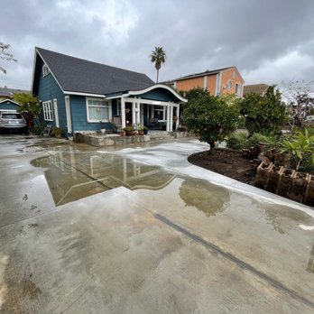 Concrete Plus - a wet driveway with a house in the background - General Contractors Near Me
