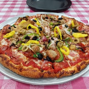 Antonios Pizza - a pizza on a plate on a checkered tablecloth - Italian Near Me - Belpre, Ohio