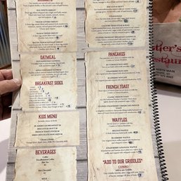 The menu is divided into sections including omelets, oatmeal, breakfast sides, kids menu, beverages, and traditional favorites. It lists specific dishes such as veggie lovers omelet, egg white omelet, and stuffed croissant breakfast sandwich, along with prices. The traditional favorites include American breakfast, biscuits & gravy, steak & eggs, and stuffed croissant sandwich. The menu also offers pancakes, French toast, waffles, and add-on options for grilled items. Beverages include coffee, hot tea, hot chocolate, milk, and juice.
