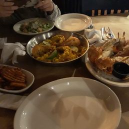 Lobster and languistine paella, at the center, grilled lobster at the right. Side dishes of sweet potato fries and caesar salad included. Lobster and languistine paella, at the center, grilled lobster at the right. Side dishes of sweet potato fries and caesar salad included.
