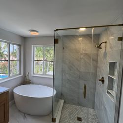 Rapid Handy - Modern bathroom remodel featuring a walk-in glass shower, custom tile work, and freestanding tub completed by Rapid Handy Inc.