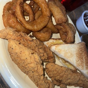 Eagle Guest Ranch - A plate with fried onion rings, chicken tenders, and a grilled cheese sandwich, accompanied by a cup of soda and a small cup of dipping sauce. - Cafes Near Me - Datil, New Mexico