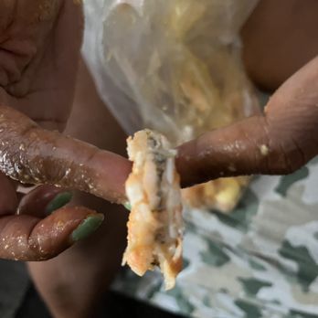 The Boiling Crab - a woman holding a piece of food - Seafood Near Me - Richmond, Virginia