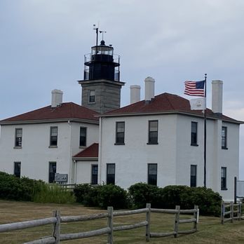 Beavertail Lighthouse - A white historic lighthouse building with a black tower and red roof, featuring American flags, located at Beavertail Lighthouse in Jamestown, Rhode Island. - Landmarks & Historical Buildings Near Me - Jamestown, Rhode Island
