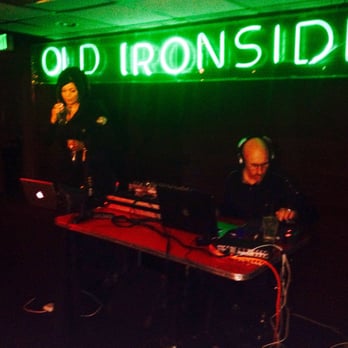 UNDERTONE - a man playing a dj in front of a neon sign that reads old ironside - Dance Clubs Near Me - Sacramento, California