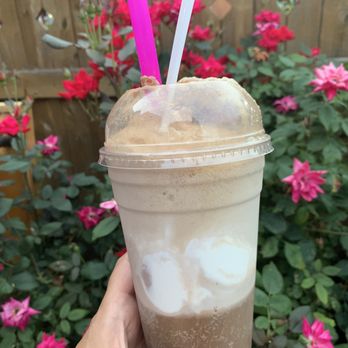 Saugatuck Sweets - Root beer float - A root beer float with ice cream in a clear plastic cup, two straws, held outdoors near pink flowering bushes and a wooden fence. - Ice Cream & Frozen Yogurt Near Me - Fairfield, Connecticut