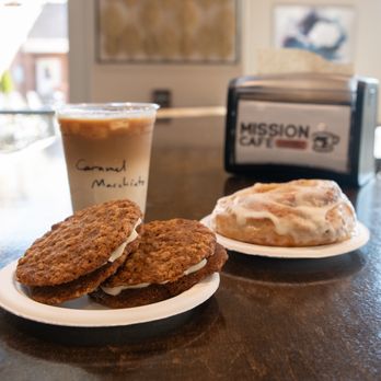 Mission Cafe - Iced Caramel Macchiato, Oatmeal Pies, and Cinnamon Bun arranged on bar table - Coffee & Tea Near Me - Burlington, North Carolina Mission Cafe - Iced Caramel Macchiato, Oatmeal Pies, and Cinnamon Bun arranged on bar table - Coffee & Tea Near Me - Burlington, North Carolina