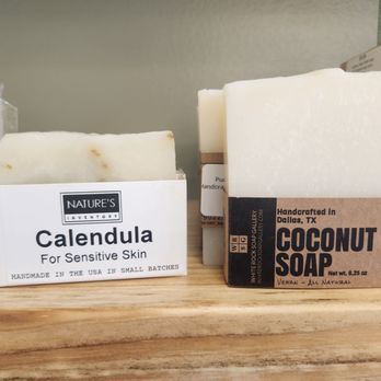 Cloverleaf Nook - Handmade soaps (In the great U.S. of A) - Bars of handmade soap, such as calendula for sensitive skin and coconut soap, are arranged on a wooden surface, with labels indicating their ingredients and origin. - Gift Shops Near Me - Culpeper, Virginia