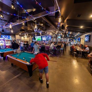 Brewbury - A vibrant wide-angle view of Brewbury's interior featuring pool tables, arcade games, full dining tables, and massive TV scre... - Sports Bars Near Me - Middlebury, Connecticut