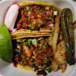 El Dorado Taco Truck - Two pork tacos with cilantro, onion, and hot sauce. Radishes, piece of lime, grilled onions and half jalapeno on the side.