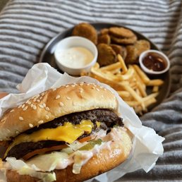 a hand holding a cheeseburger and fries