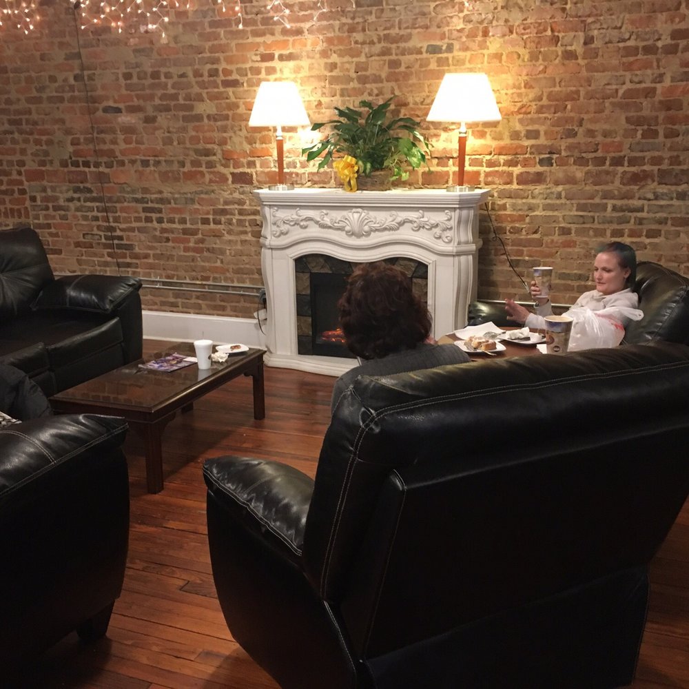 The Sidewalk Cafe - a woman sitting on a couch in front of a fireplace - Coffee & Tea Near Me - Sumter, South Carolina The Sidewalk Cafe - a woman sitting on a couch in front of a fireplace - Coffee & Tea Near Me - Sumter, South Carolina